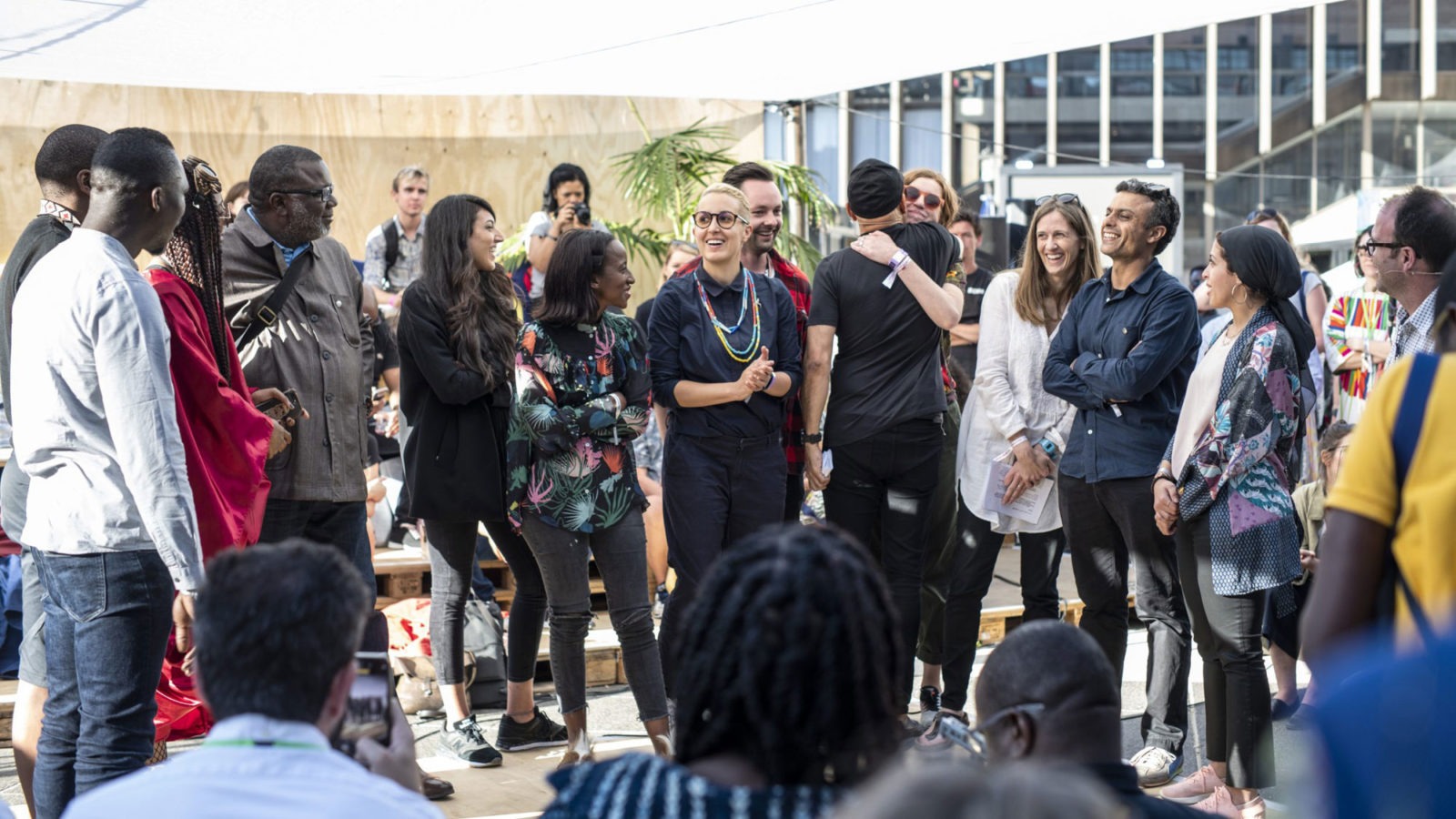 Large diverse group of people laughing and talking in front of an audience.