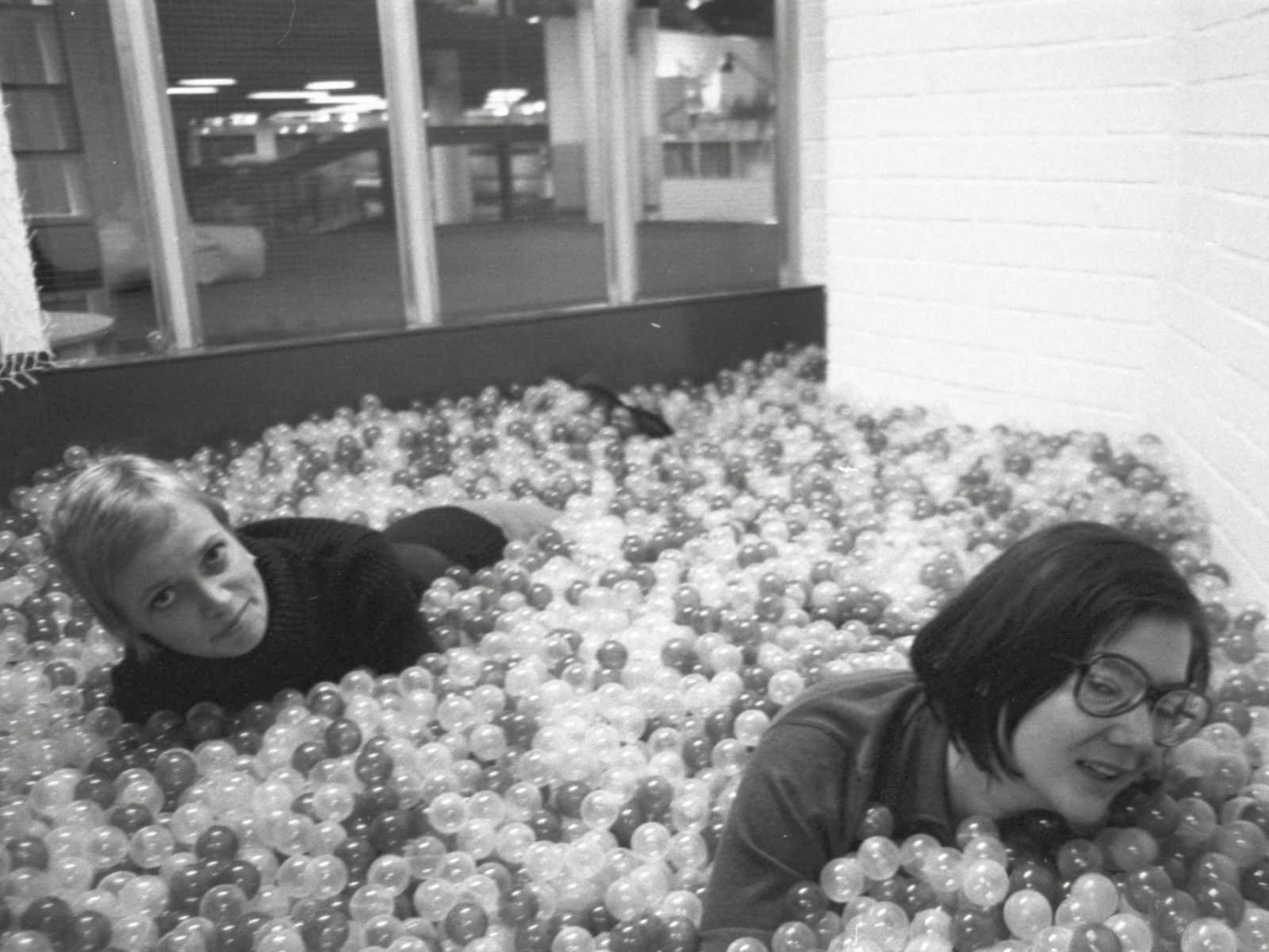 Two young women in a ​​ball room, one blonde, the other dark-haired with glasses.