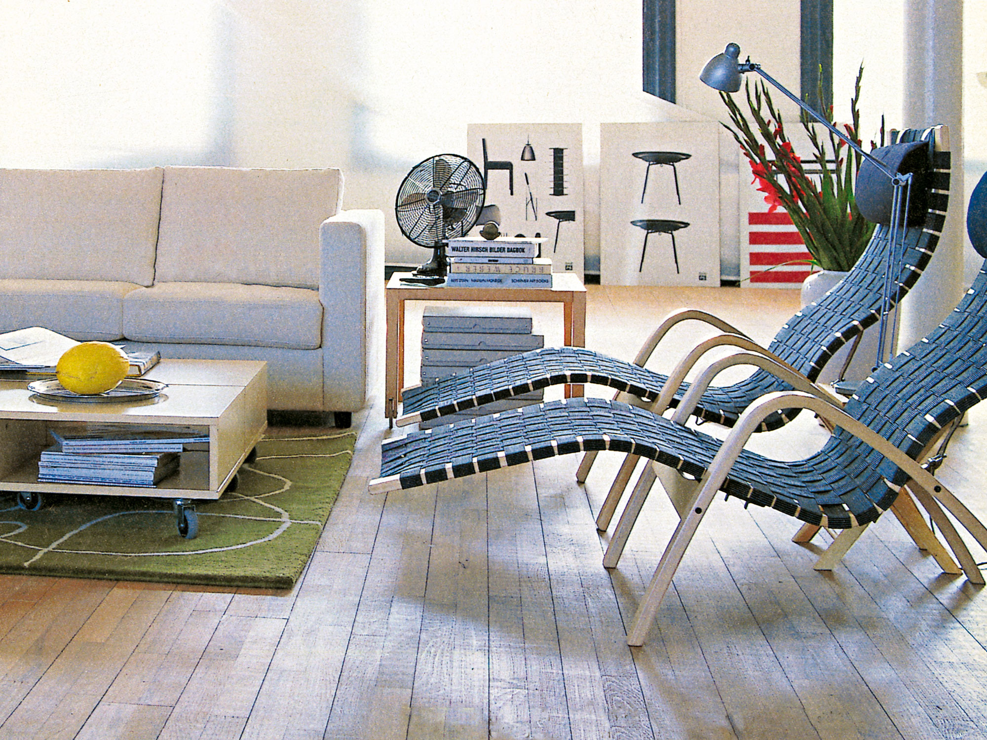 Minimalist interior, 1990s Scandinavian style, white sofa, 2 recliners, blond wood side tables in front of large windows.