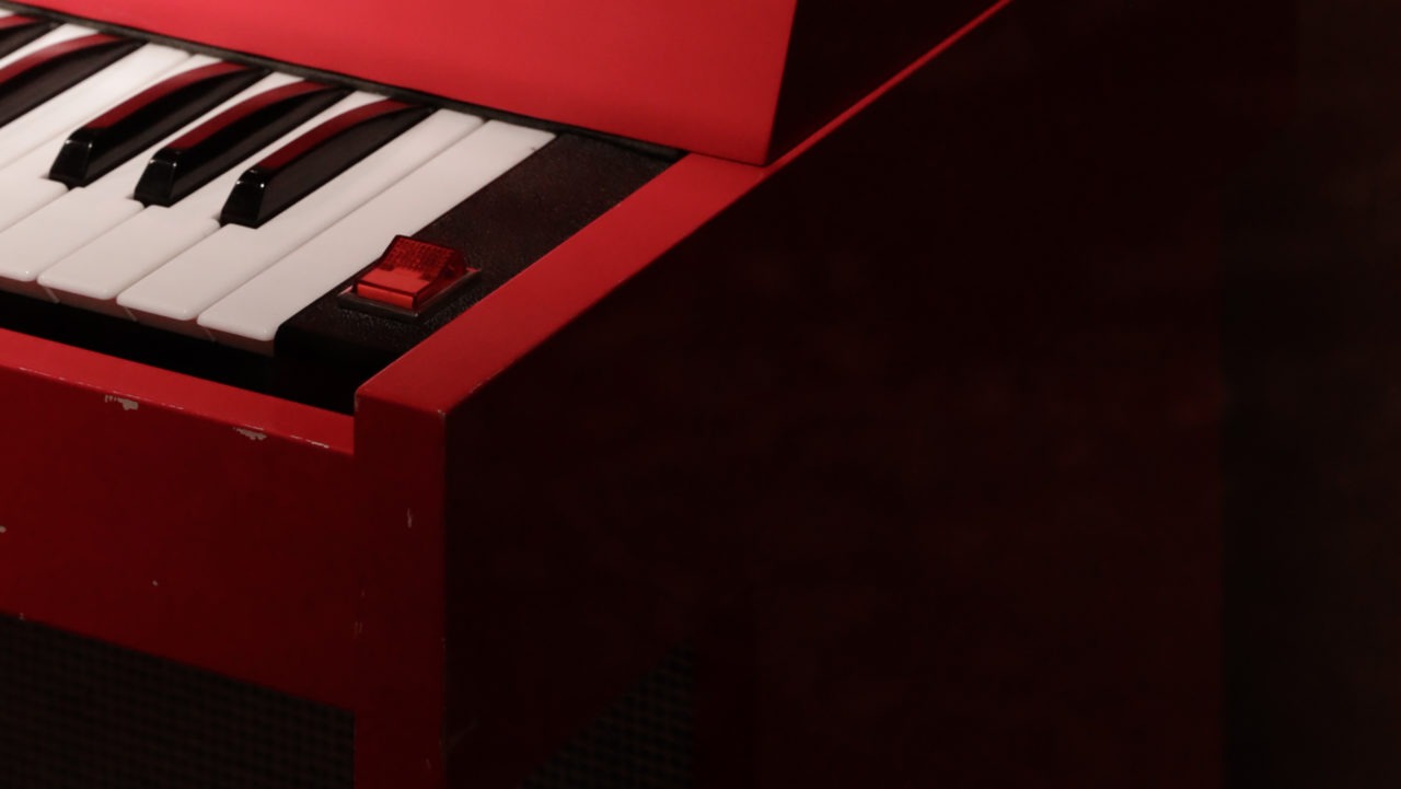 The corner of a red IKEA RENN piano with a red electric switch.