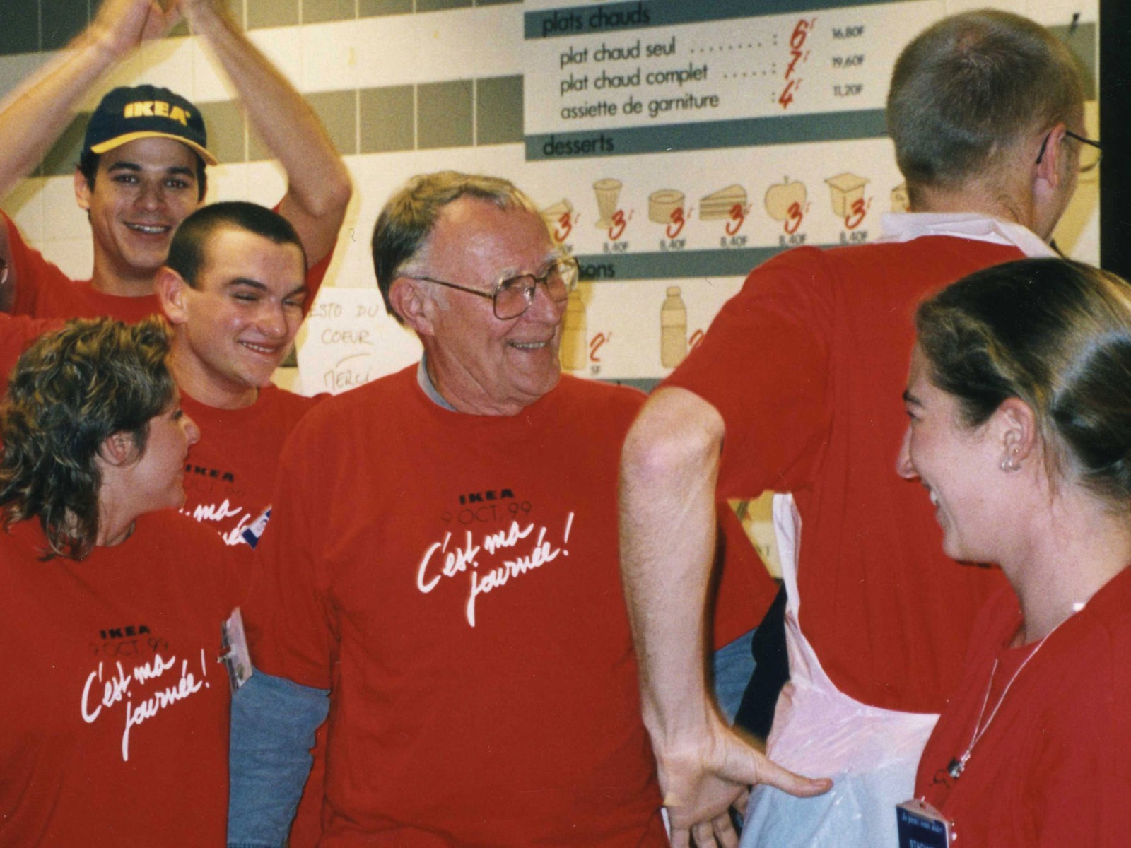 Ingvar Kamprad with IKEA staff, all smiling and wearing red T-shirts with text IKEA 9 Oct 99, C'est ma journée – it’s my day.