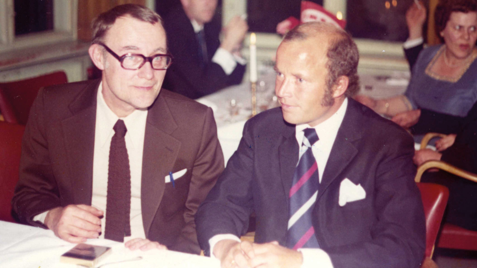 Ingvar Kamprad, brown suit and tie, Jan Johannessen, dark suit, striped tie, in restaurant with white tablecloths.