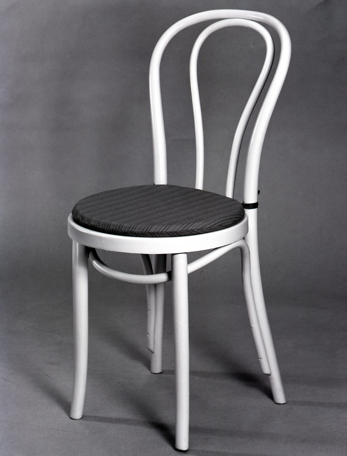 Białe krzesło z siedziskiem w ciemne paski.