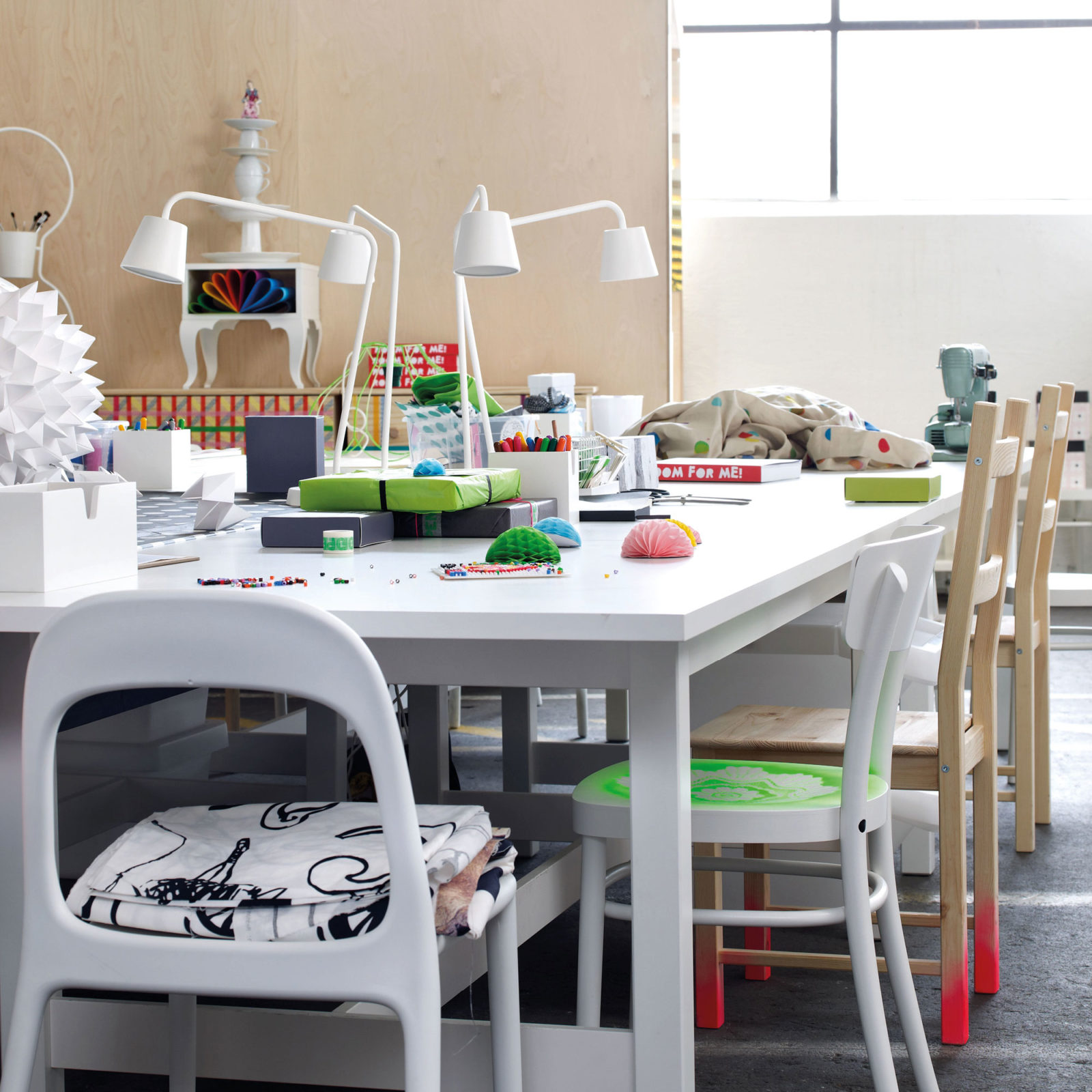 White table scattered with hobby materials and wrapped presents. A sewing machine visible in the background.