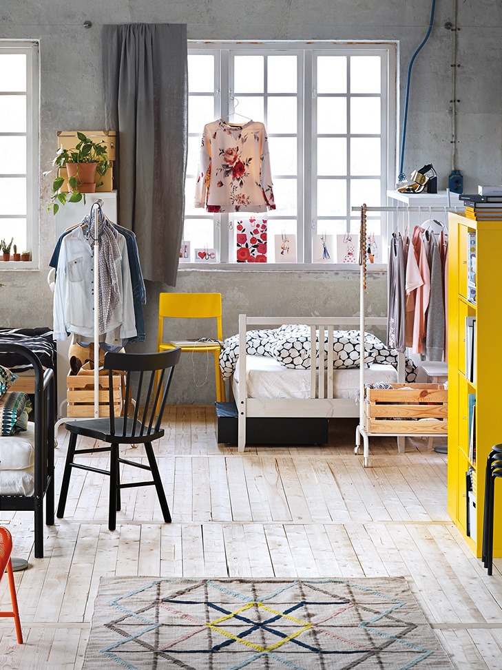 Bedden, stoelen en opbergmeubels in gedurfde maar ook rustige kleuren, als eilanden in een grote ruimte met houten vloeren.