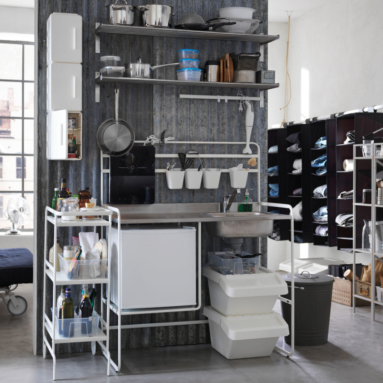 Połączenie pomieszczenia gospodarczego i różnych rozwiązań do przechowywania zasłania ściankę działową w dużym pokoju z wysokim sufitem.