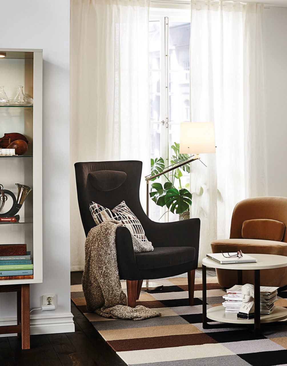 Två fåtöljer, en i brun sammet, den andra i orange sammet, framför ett fönster med tunna vita gardiner.