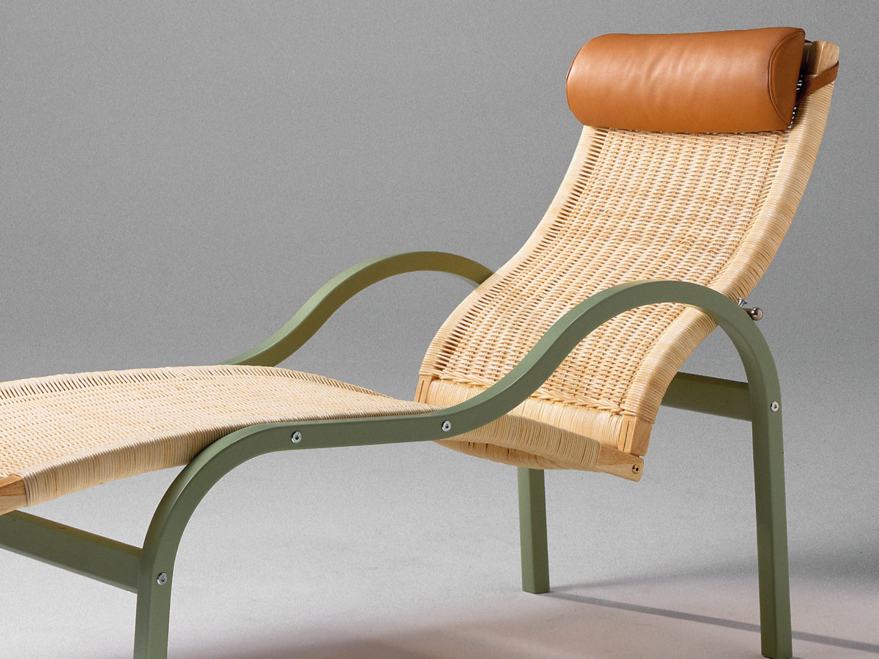 Vilfåtölj i rotting med grön ram och läderdetaljer.