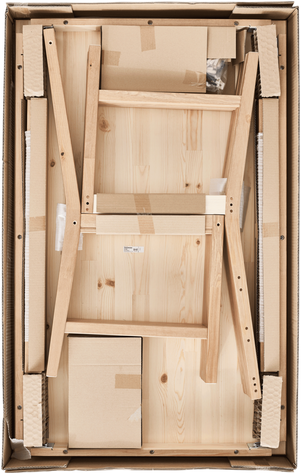 Öppnat platt paket från IKEA sett ovanifrån med delarna till en möbel i ljust trä.