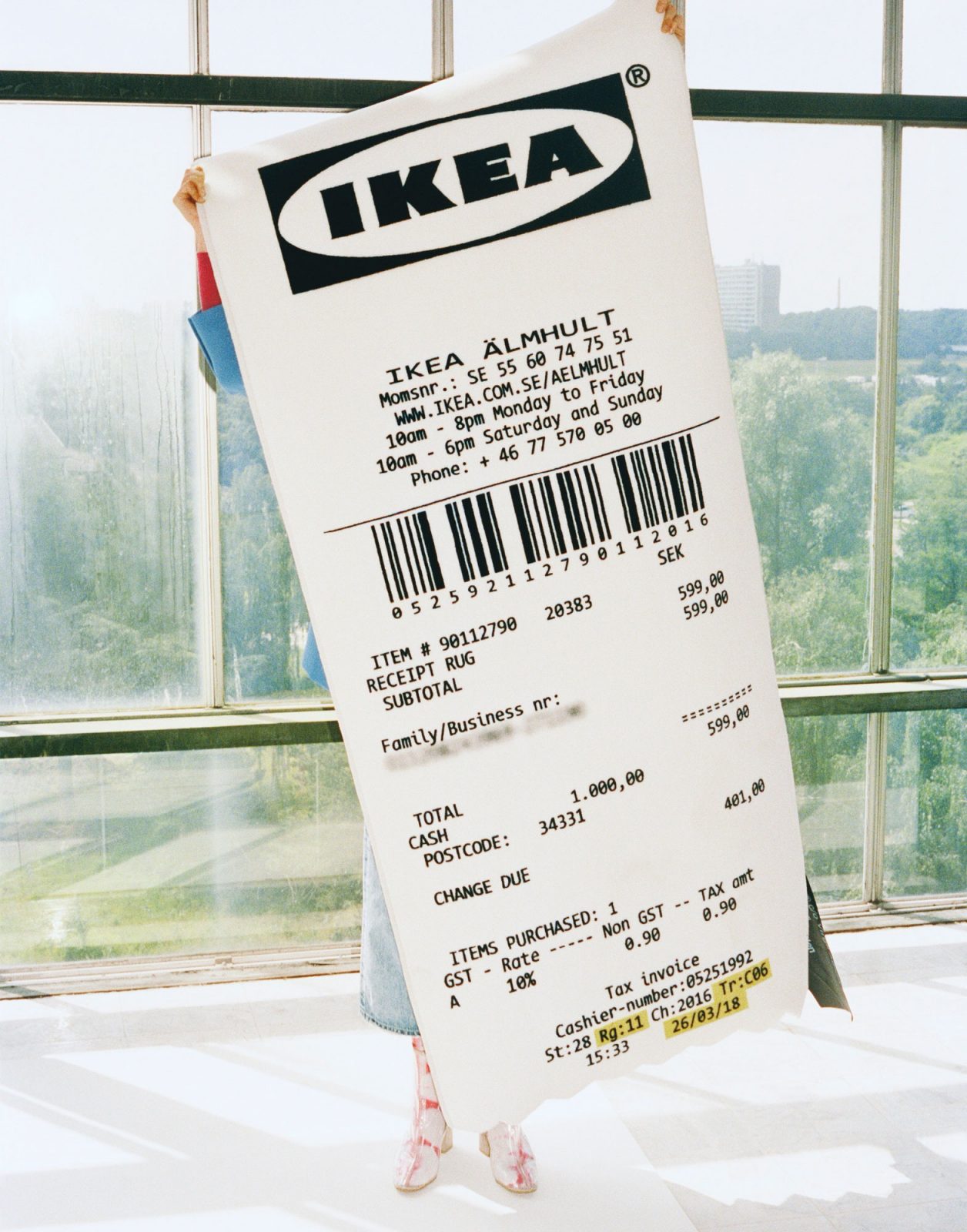 Person håller upp matta som ser ut som ett enormt kassakvitto från IKEA.