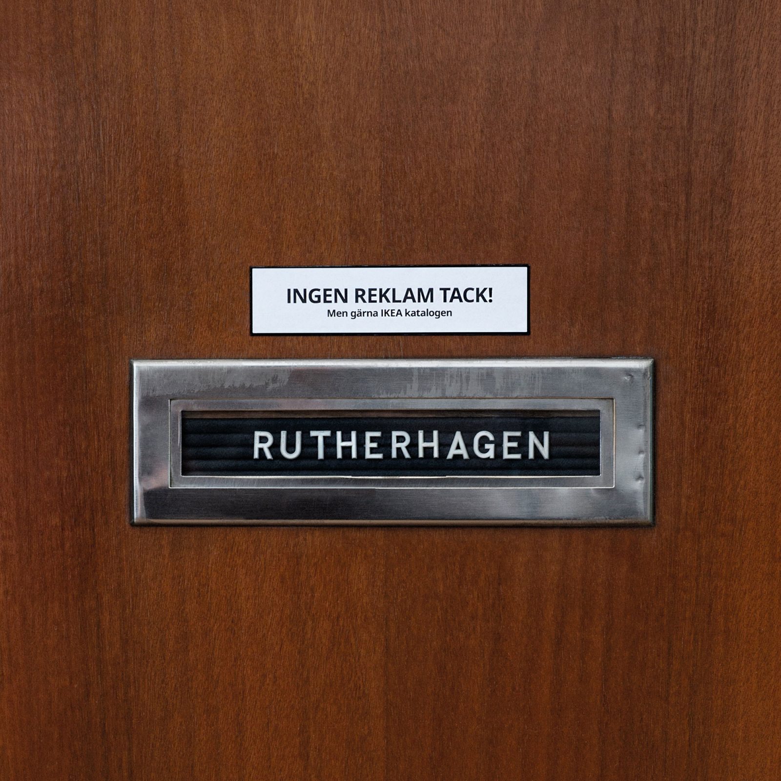 Letterbox on brown apartment door with sign 