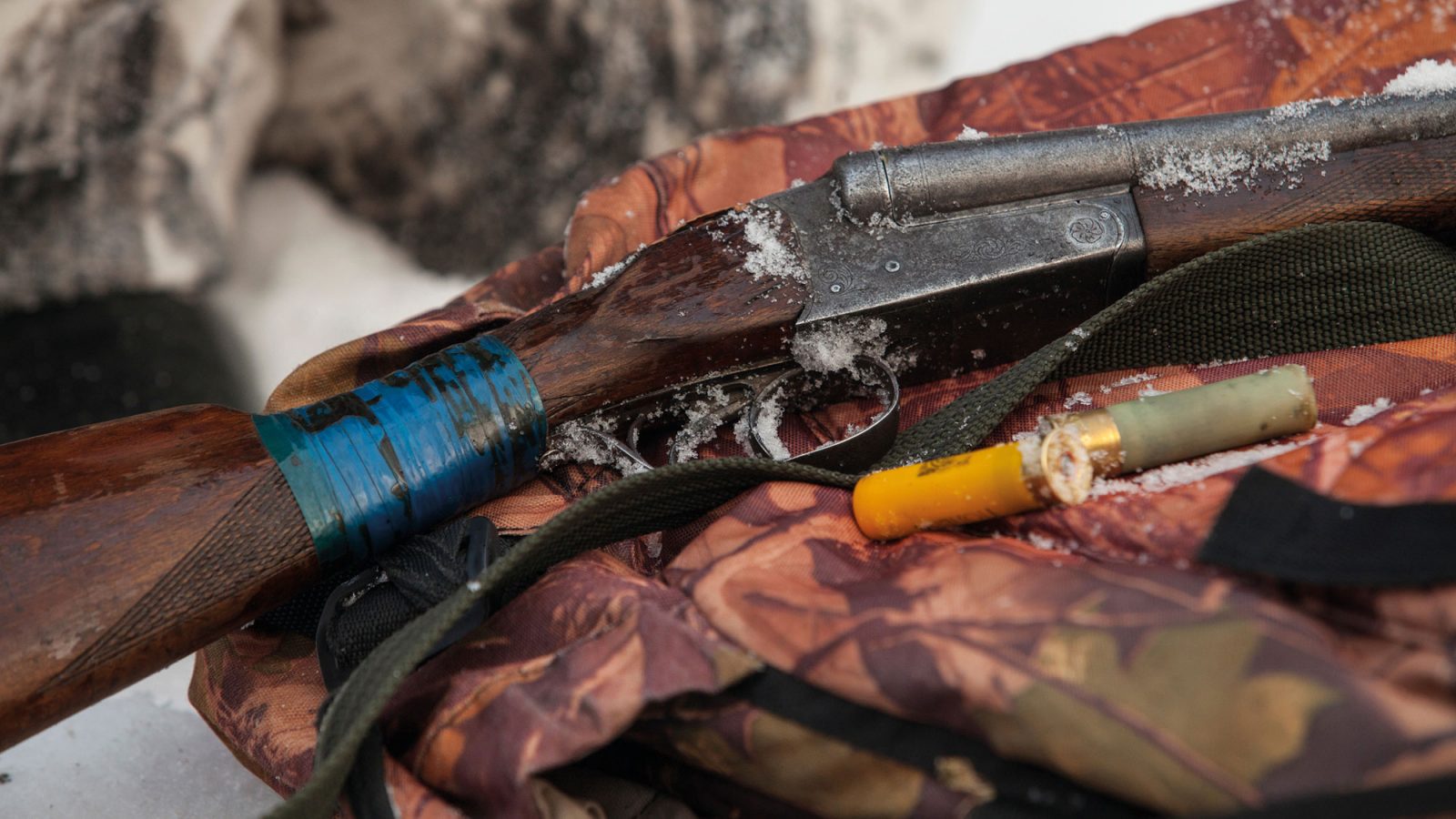 Gevär, ammunition och kamouflagemönstrad ryggsäck.