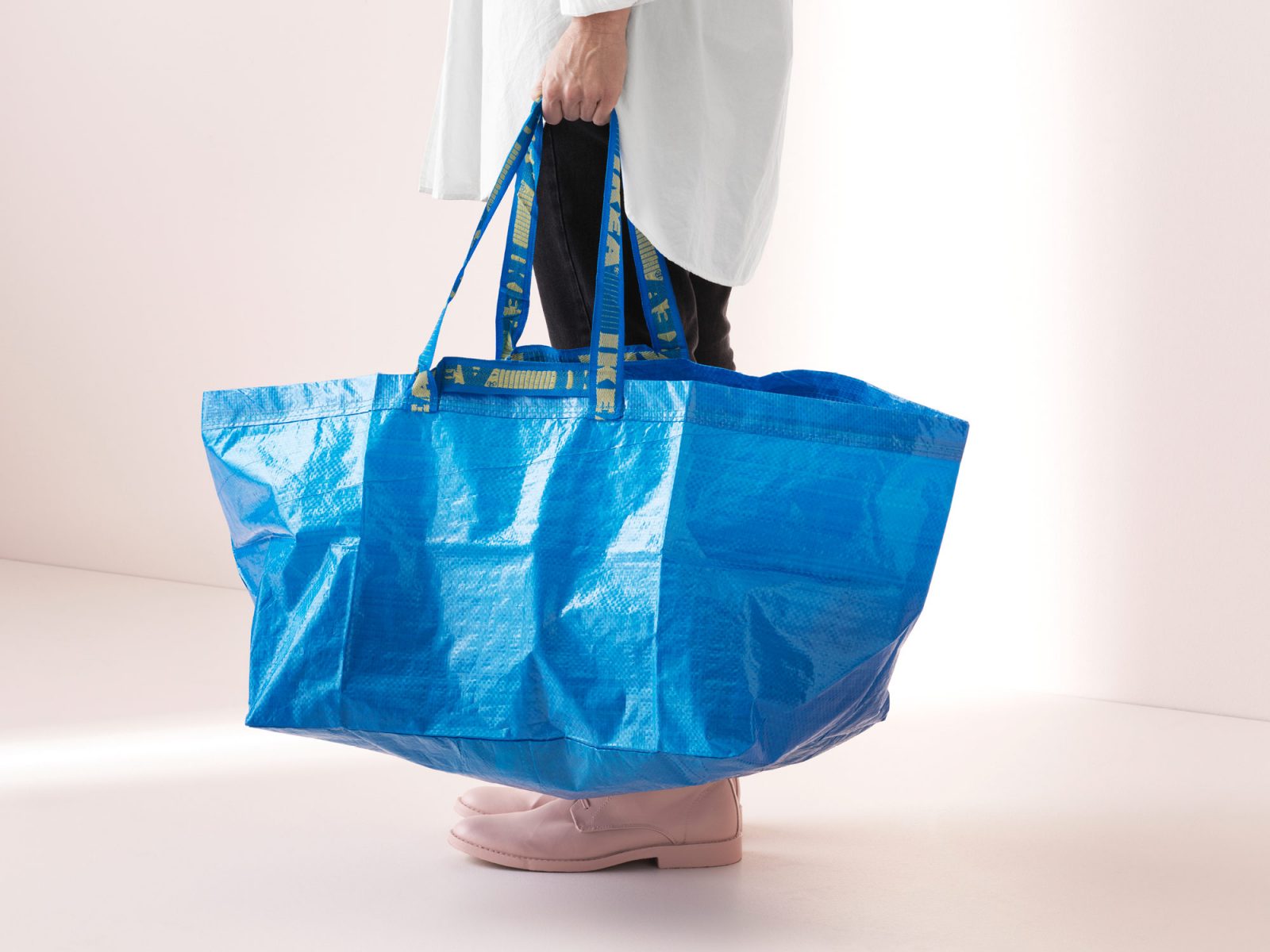 Eine Person hält eine blaue FRAKTA Tasche in der Hand. Nur die untere Körperhälfte ist zu sehen.