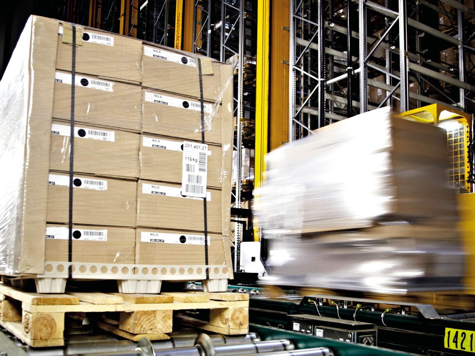 Delar av en möbel i ljust trä är noggrant packade i en stor platt papperskartong med locket uppfällt.