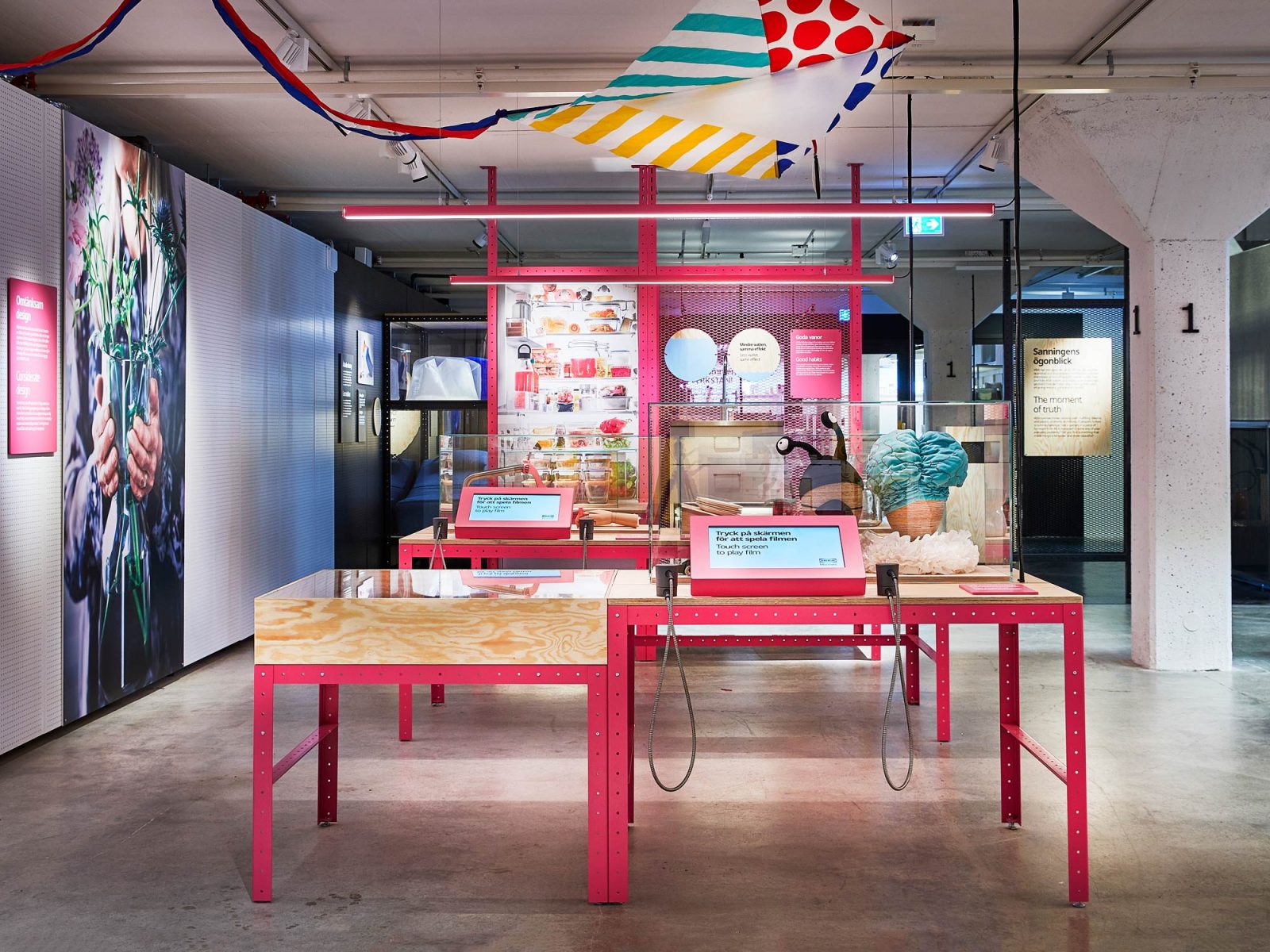 Pinker Tisch mit Schirmen und buntem Stoff aus der Ausstellung.
