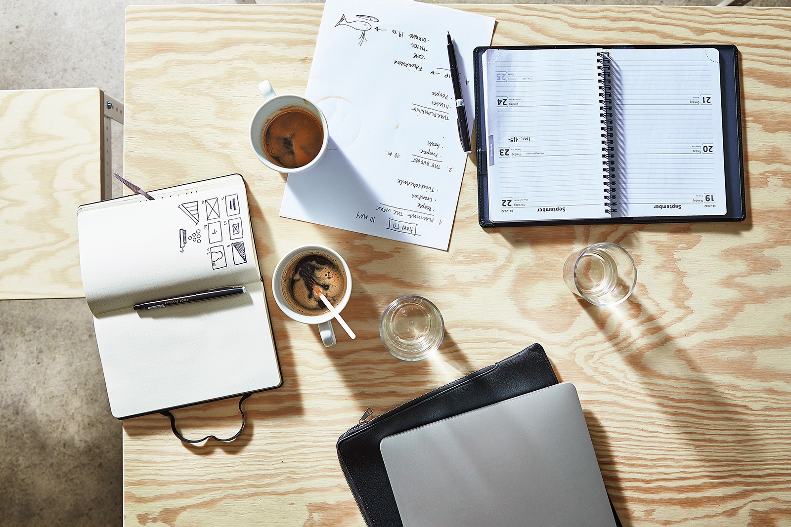 Notebooks, calendar and cups of coffee on a table.