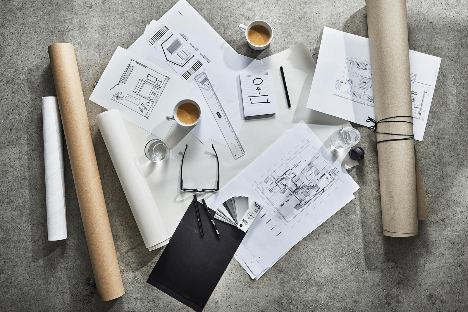 Drawings, rulers, glue and coffee cups scattered on a stone table.
