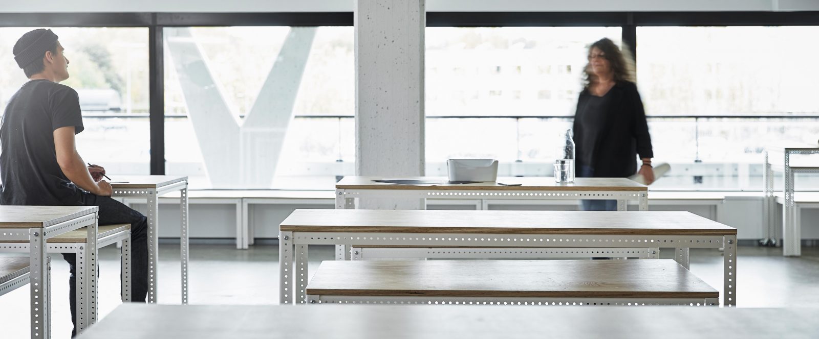 Two people meeting up in a room with large window sections.