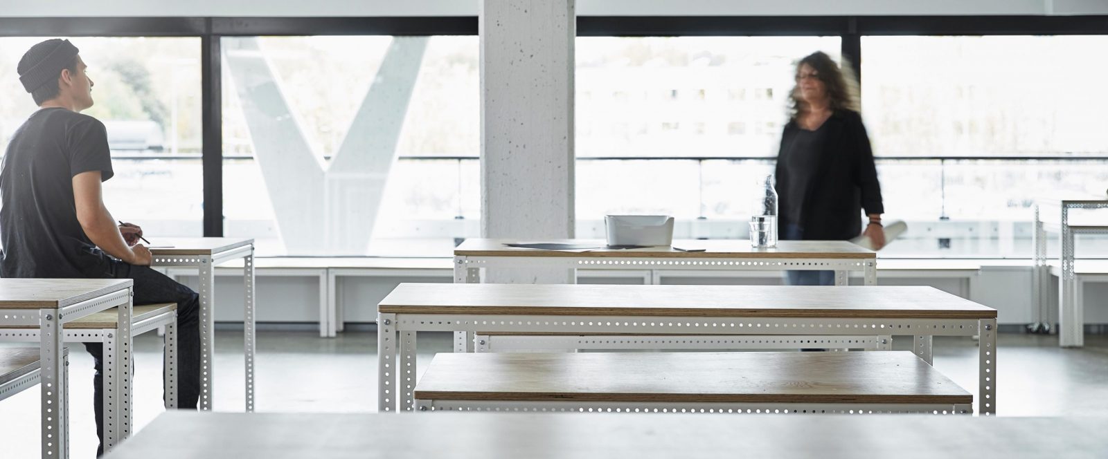 Two people meeting up in a room with large window sections.