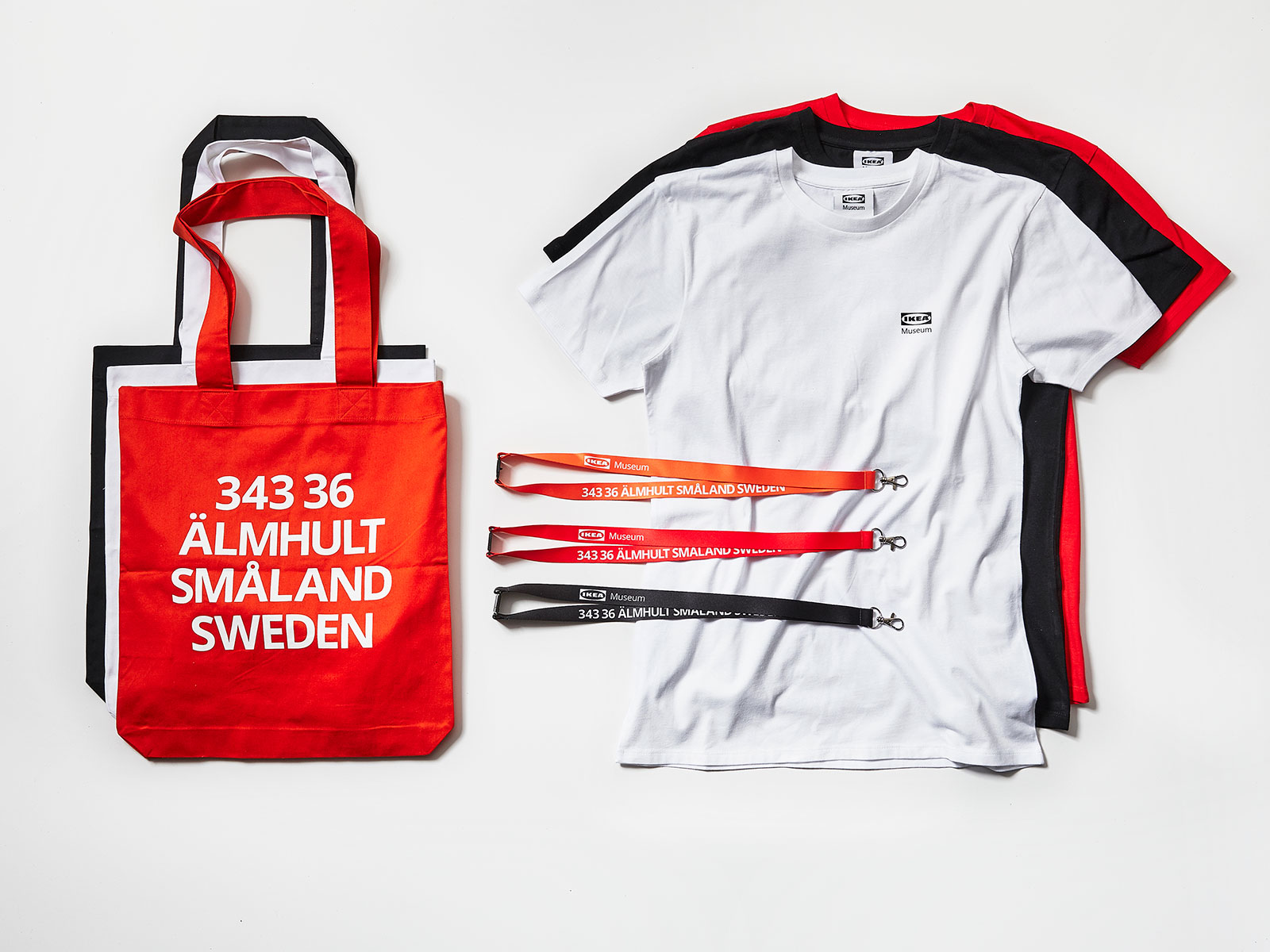 T-Shirts, Hoodies, Tabletts, Thermoskannen und Beutel in Rot, Orange und Schwarz, Aufdruck 343 36, ÄLMHULT SMÅLAND SWEDEN.
