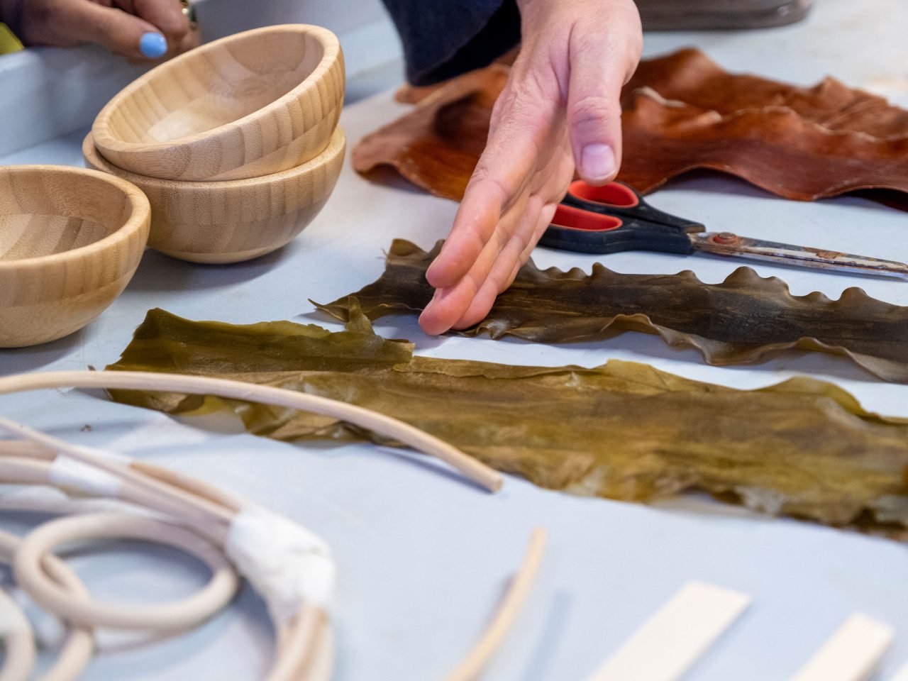 Close-up of hands during a workshop, table scattered with different materials.