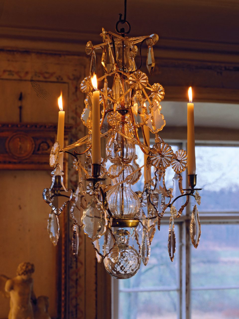 Large chandelier in Gustavian style with hanging crystals and lit candles.