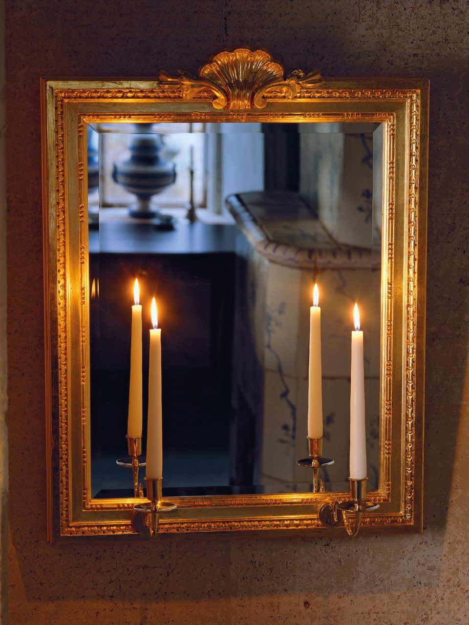Mirror sconce in Gustavian style with gilded frame and two lit candles.