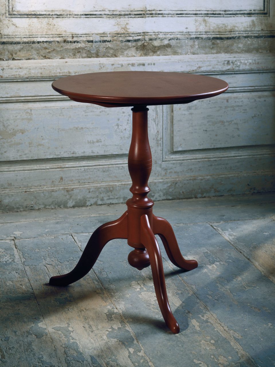 Small brown wooden table in Gustavian style standing in a worn setting.