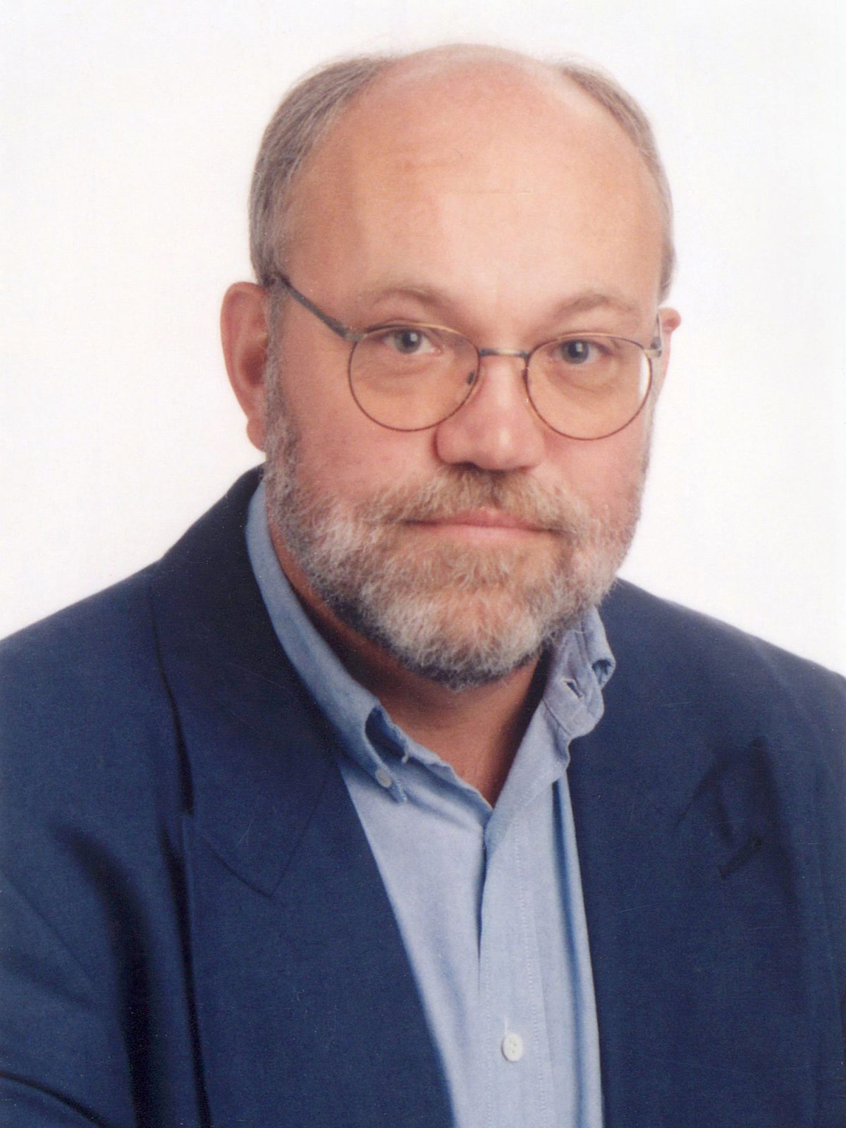A middle-aged man with glasses, blue blazer, and light blue shirt, Thomas Blomqvist.