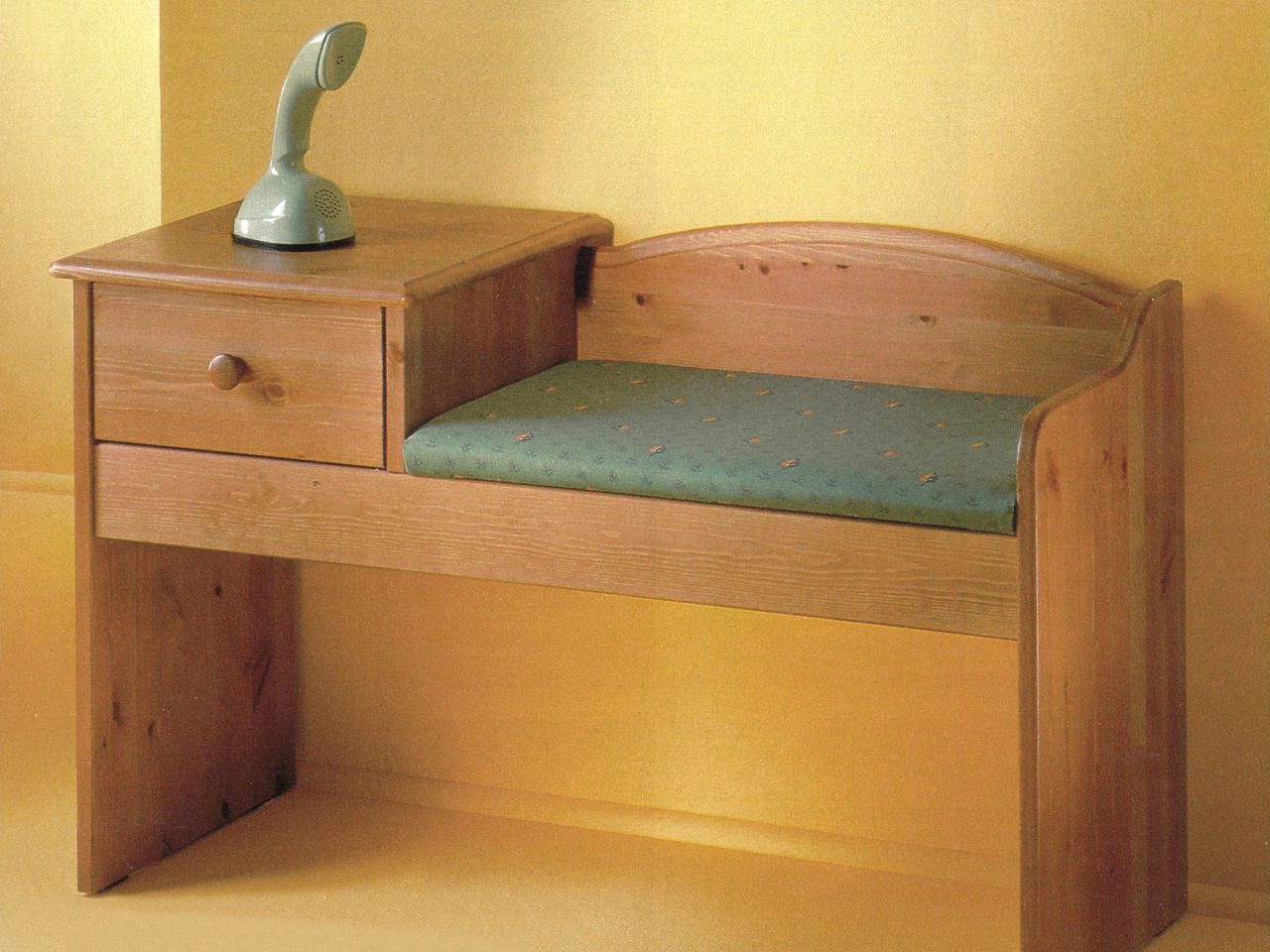A mint green 'Cobra' phone sits on hall table DÄVERT made of birch wood, the seat covered with dark green seat cushion.