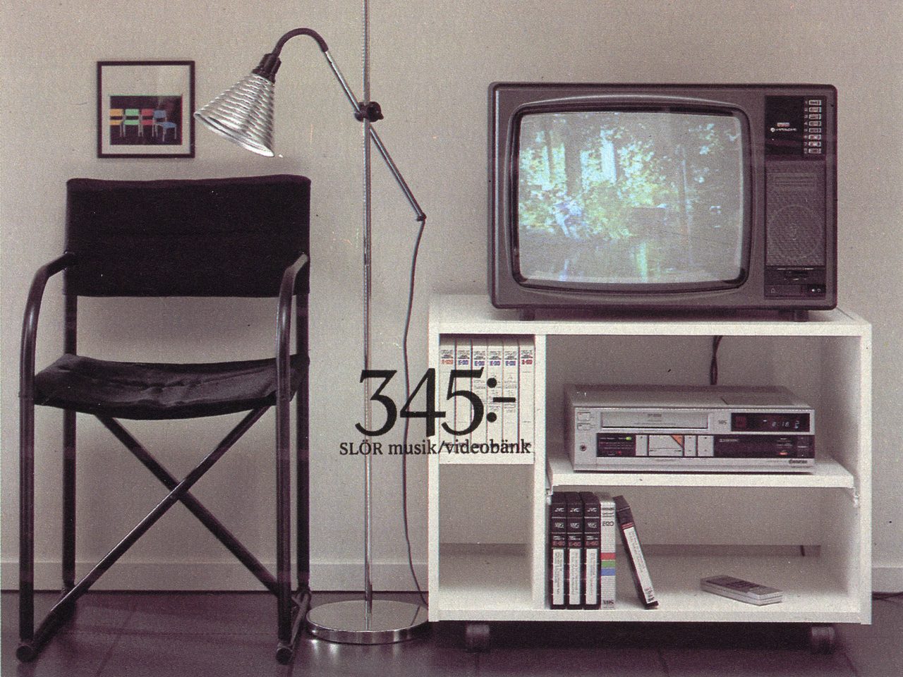 Svart regissörsstol står bredvid tjockteve på vit musik- och videobänk i 1980-talsstil.