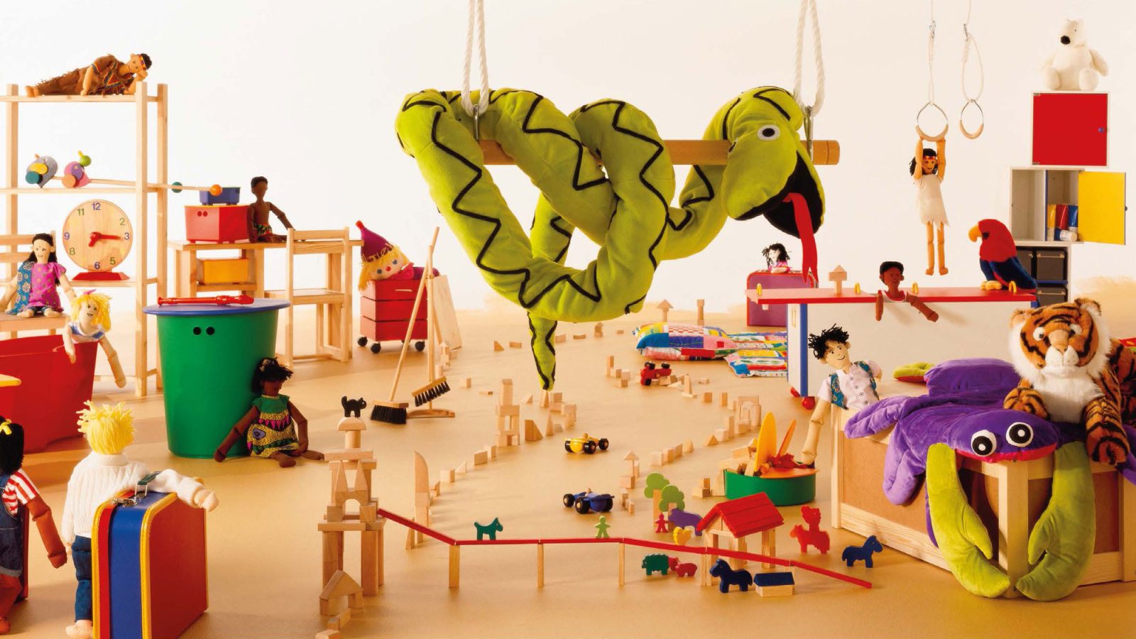 A large room filled with toys, including a large green soft toy shaped like a snake and another shaped like a big crab.