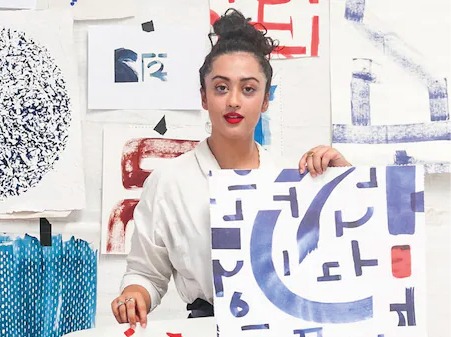 Mörkhårig kvinna i vit skjorta, Akanksha Deo, omgiven av färgglada skisser.