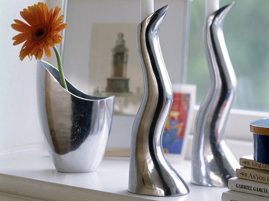 Chrome-coloured metal vase and candlesticks with soft, rounded shapes.