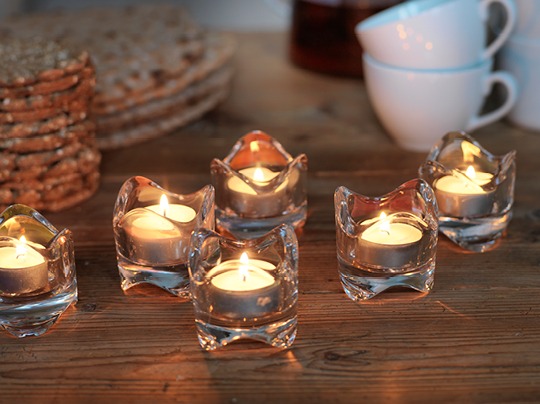 Lit tealights in holders made of pressed clear glass.