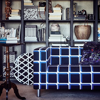 Soffa med ett djärvt svart, vitt och blårutigt mönster står framför en bokhylla.