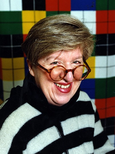 Leende gråhårig kvinna, Inez Svensson, med runda glasögon och randig tröja.