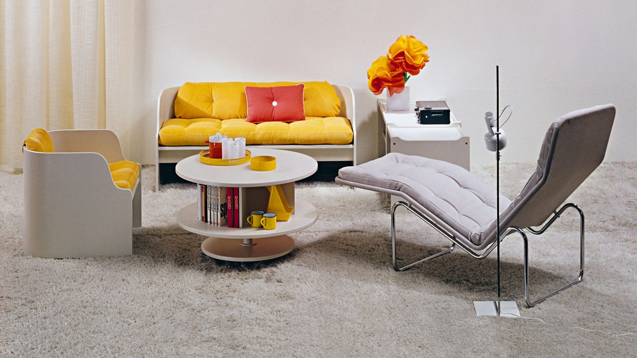 Trendy 1960s living room with white lounger and wooden furniture with yellow and red pillows.