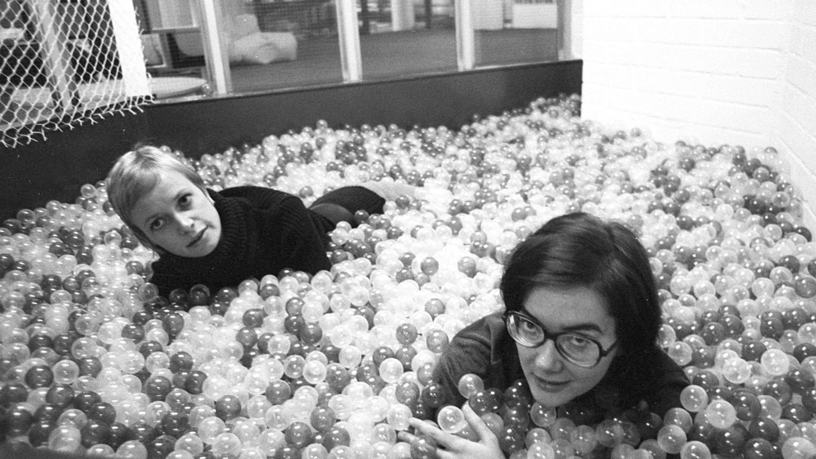 Två unga kvinnor leker i ett stort bollhav.