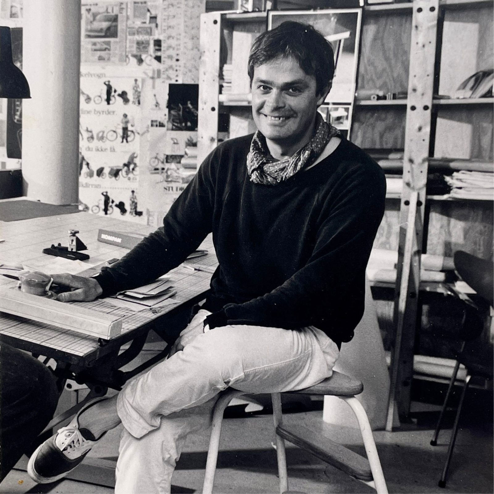 Leende ung man sitter vid ritbord.