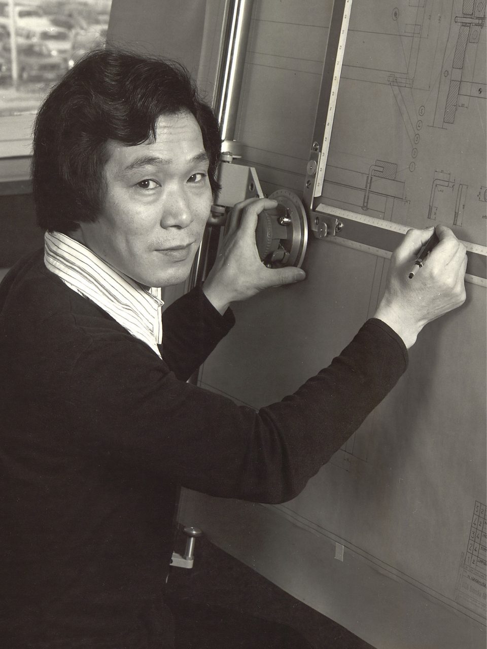 Young Japanese man, Noboru Nakamura, works at a drawing table.