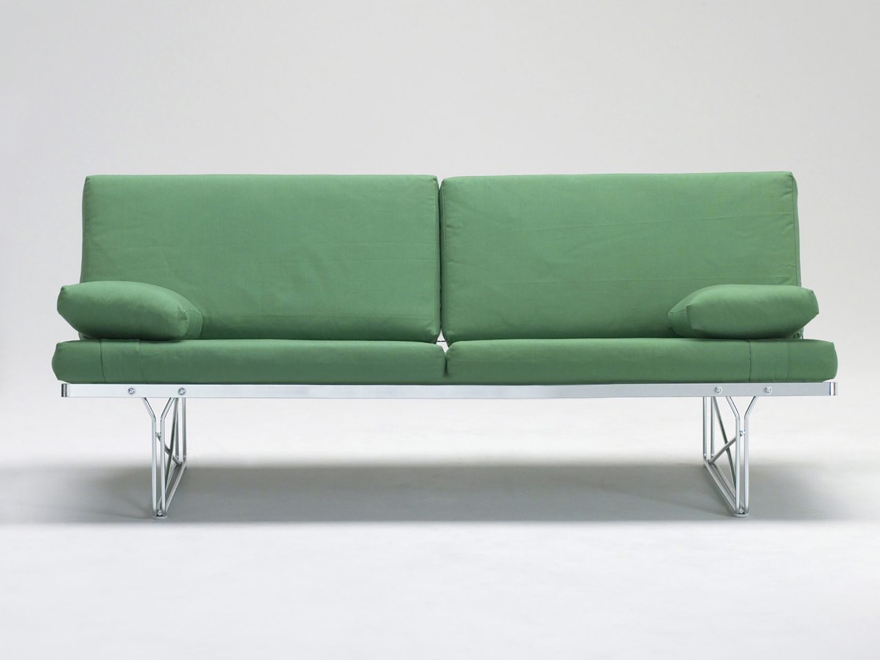 Stilren, enkel grön soffa på stålunderrede.