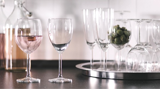Wine glasses in different shapes stand on a table and a silver tray, SVALKA.