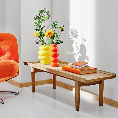 Colourful vases stand on a low wooden bench with edges to keep things from rolling off the surface.