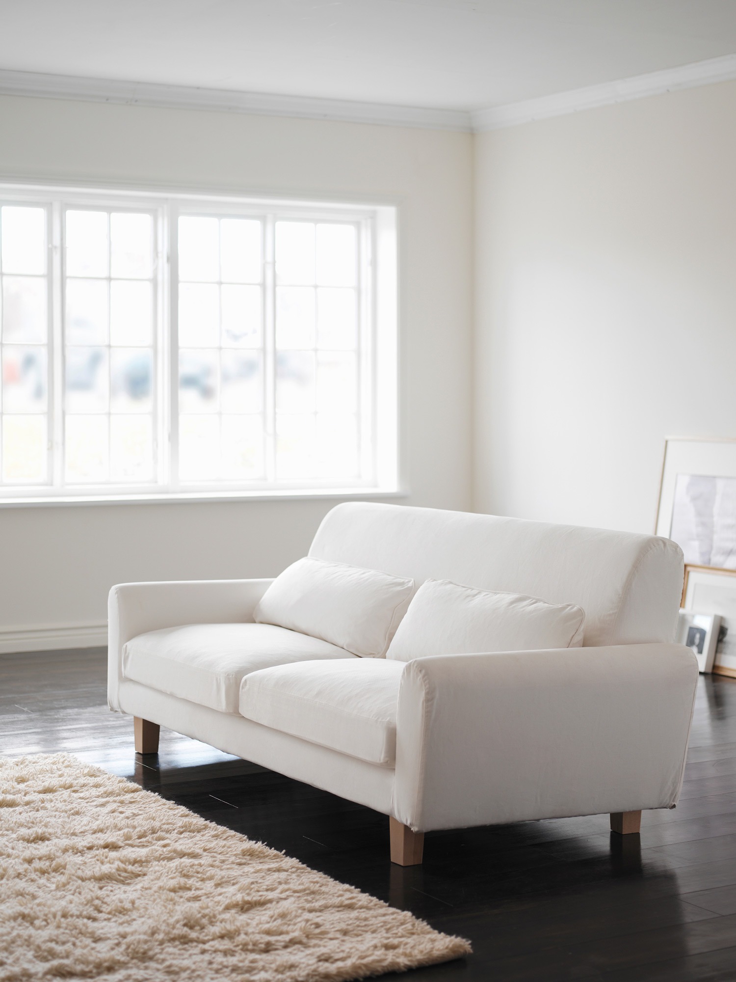 Light living room with white sofa and shaggy rug.