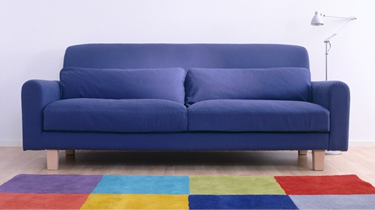 Dark blue spacious sofa, NIKKALA, on a brightly coloured rug.