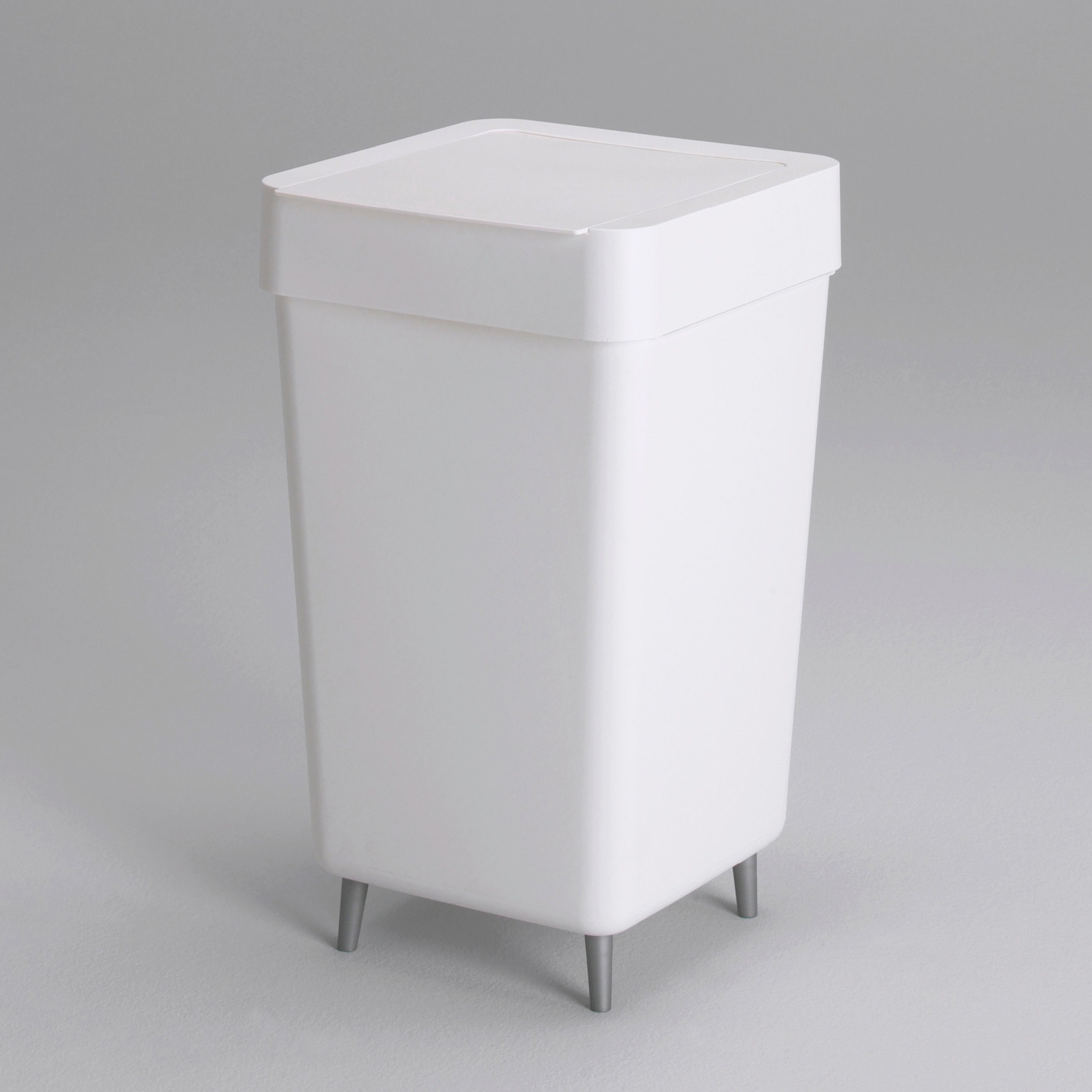 Simple white plastic waste basket, FIBBE, with metal legs.