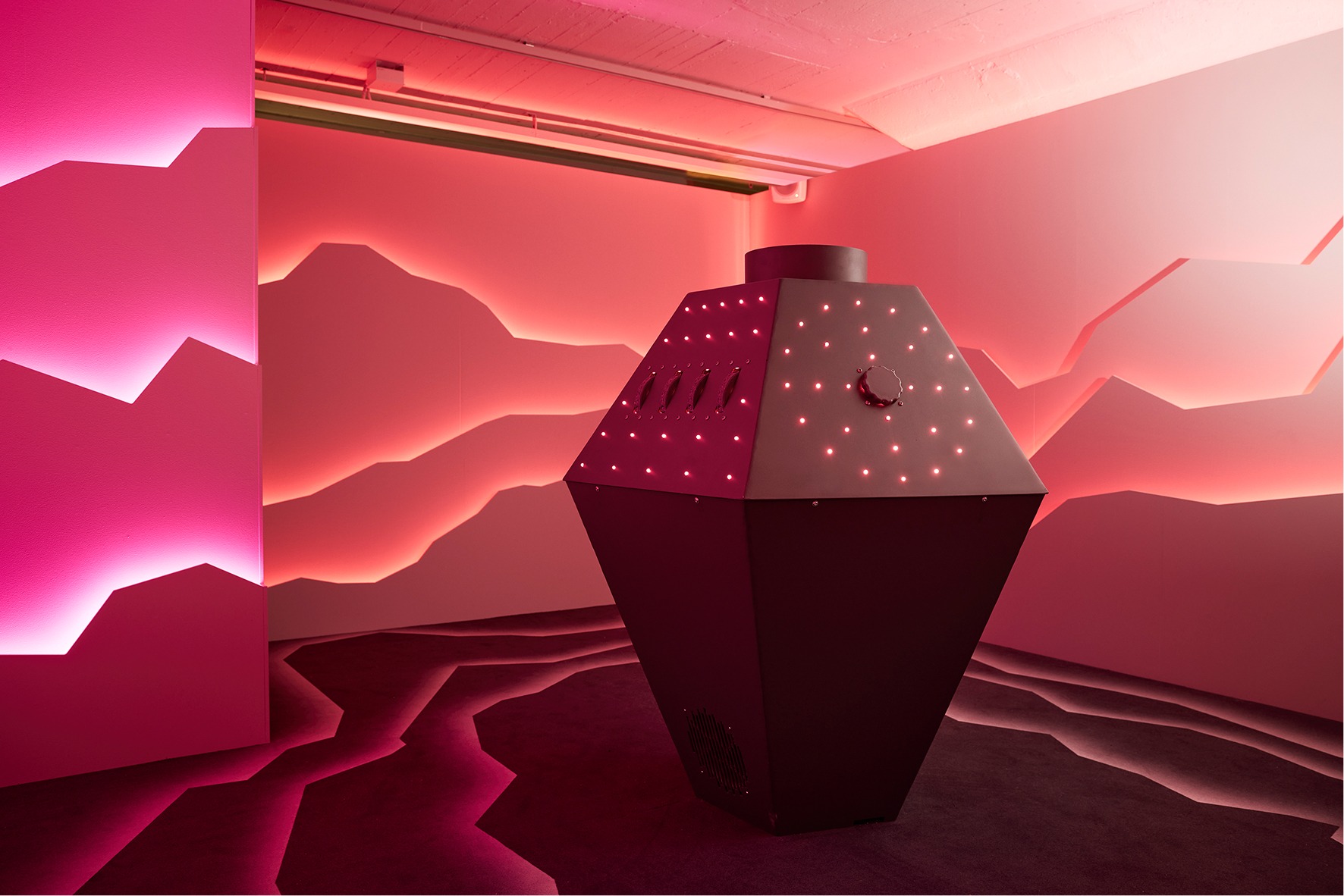 A red-lit room with an outer space theme, featuring an interactive unit in the center.