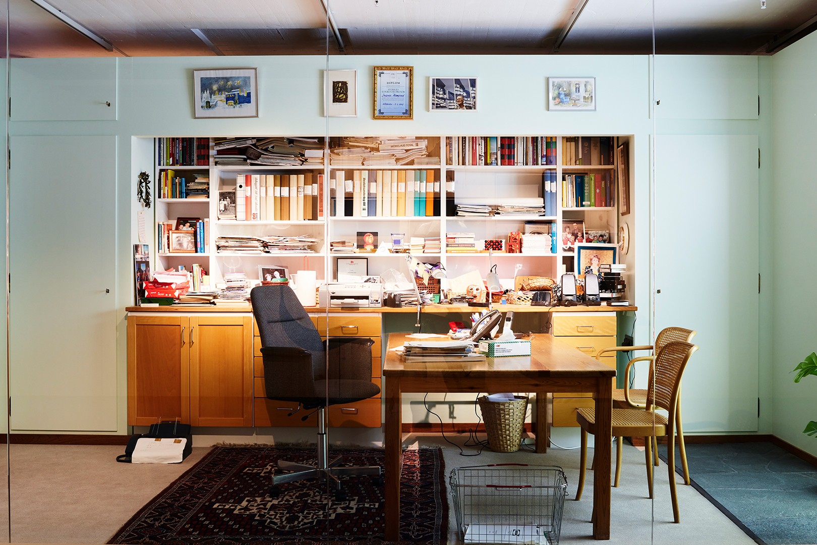 Ingvar Kamprads skrivbord med stol och bokhylla fylld med böcker, dokument och personliga föremål