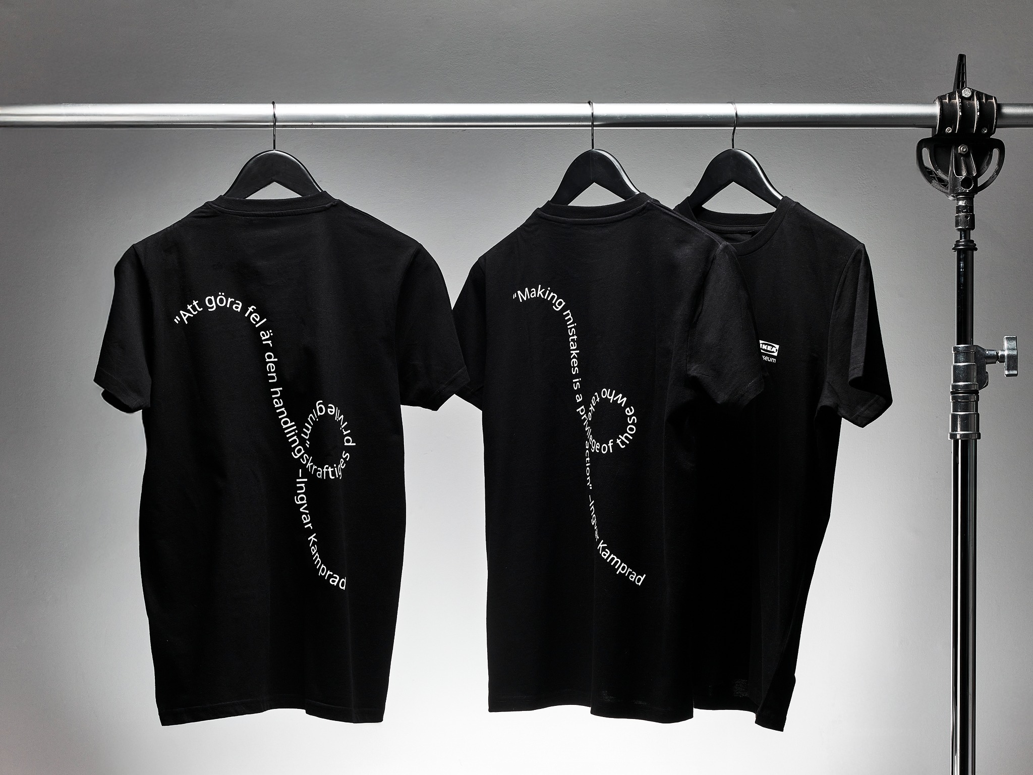 Three black T-shirts with white wavy text.